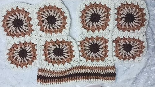 Eight sunburst granny squares laid flat above a striped crochet waistband strip, in brown, tan, and cream 