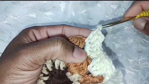 Hands joining cream and brown granny squares with a yellow hook