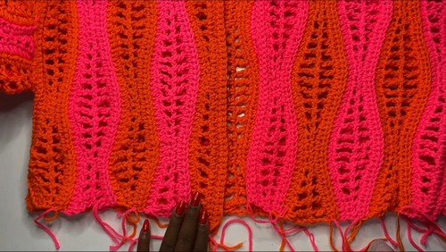 Close-up of the wavy stitch pattern, where pink and orange mesh columns curve inward and outward in an hourglass shape