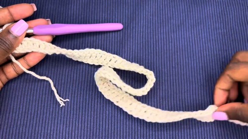 Close-up of hands working a crochet sleeve or strap in cream yarn 