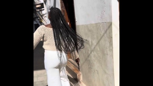 Back view of cream crochet mesh top with long braided hair, walking outdoors 