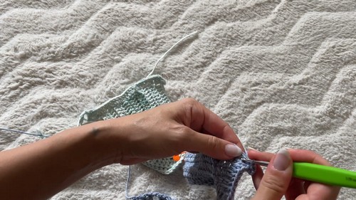 Crocheting the lace skirt panel in light blue-green yarn with hook
