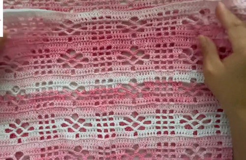 Close-up of pink and white crochet lace top fabric showing alternating diamond lace and filet grid bands 