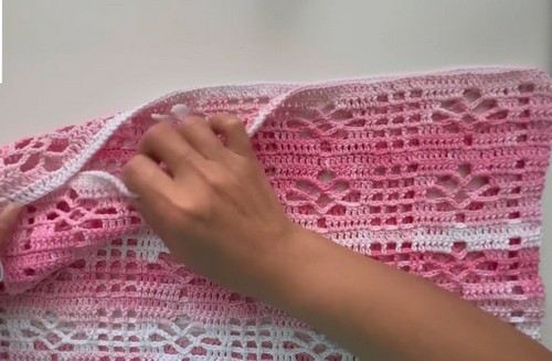Flat lay of pink and white crochet lace top panels showing open diamond stitch texture and two-color stripe construction 