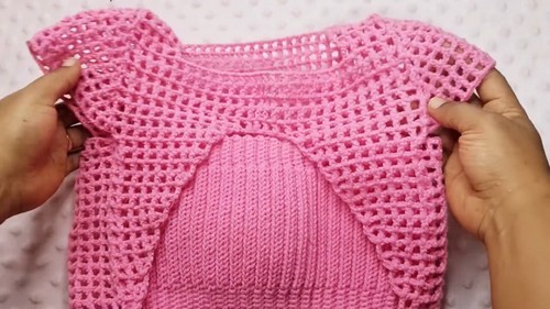 Front view of a crochet crop top showing the open cut-out section between the bust panels and the double crochet body fabric.