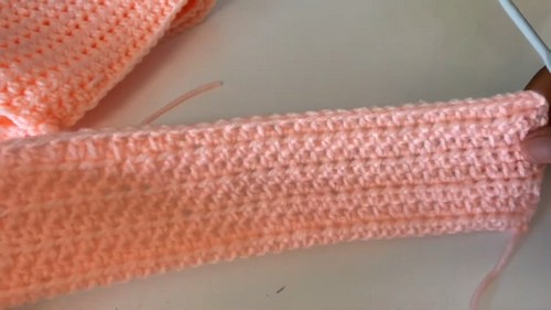 Flat lay of a long narrow peach single crochet strip with even rows, showing the waistband or cuff construction 