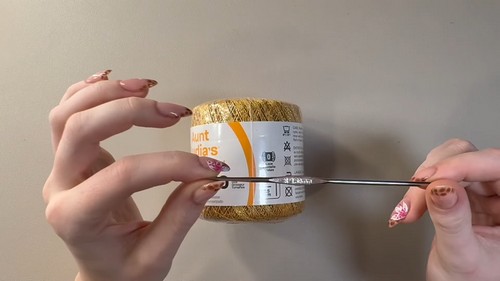 Gold metallic cotton yarn and crochet hook used for the filet crochet top