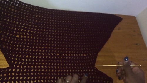 Holding a wide panel of burgundy crochet mesh fabric with hook 