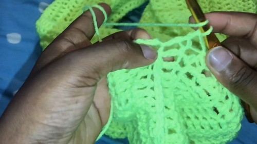 Hands building a neon green open mesh panel with a gold hook on a blue surface.