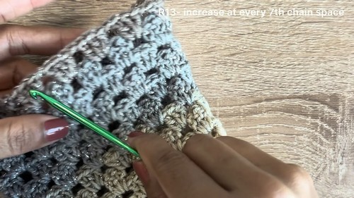 Working the granny stitch bell sleeve with a green hook, video caption showing increase instructions at every seventh chain space.