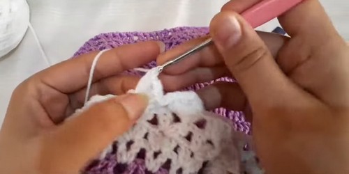 Joining the white yarn at the collar edge to begin the contrast lacy trim with a pink hook.