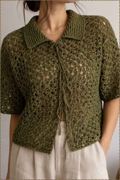 Close up of an olive green crochet cardigan showing a ribbed spread collar, tie front, and open lace body worked in olive cotton yarn