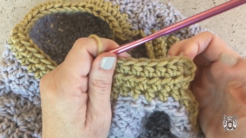 Working the mustard yellow collar section with a salmon hook, the ribbed texture of the collar band visible against the grey body fabric.