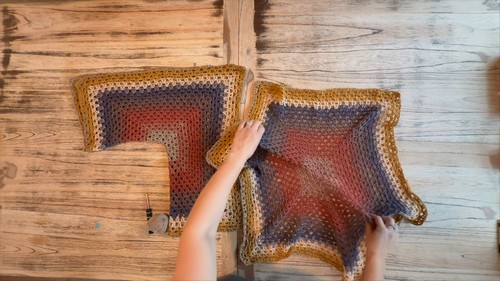 overhead view of two large completed ombre hexagon panels in gold, rust, and charcoal laid flat on a wooden table