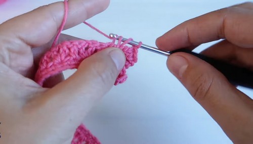 Building the collar body with a silver hook, the fabric curving naturally as rows accumulate toward the scalloped outer edge.