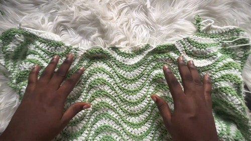 Green and cream chevron ripple crochet panel laid flat on a white fur surface showing the wave pattern