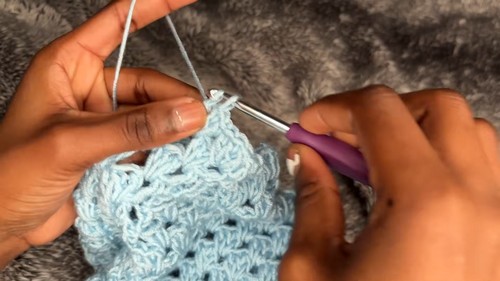 Granny stitch rows worked in light blue yarn for the crop sweater sleeve