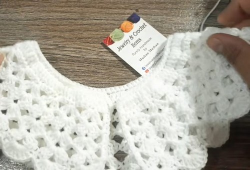 Finished crochet collar laid flat with a ribbed neckband above the openwork lace body