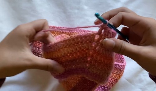 Working rows of the boat neck top body in multicolor yarn showing the folded fabric in progress.