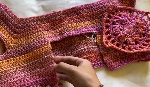 Flat layout of the boat neck top panels with a granny square motif pinned at the center front seam.