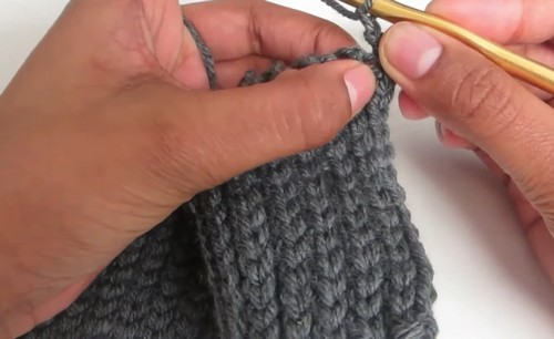 Grey ribbed crochet cuff being worked in close rows with a gold hook