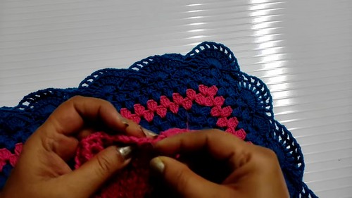 Close view of the finished navy scallop hem border with pink spike accents along the lower edge of the crochet poncho