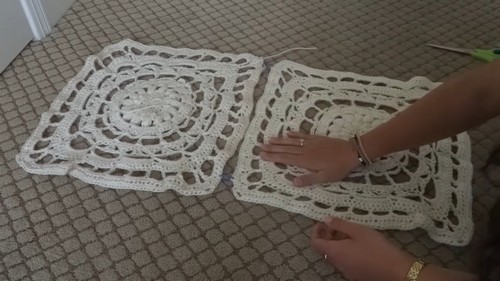 Two large cream lace crochet squares laid side by side on carpet showing the mandala center and matching border rounds