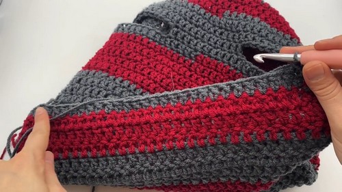 Working the edge of a leg opening on the striped dog sweater with a metal hook