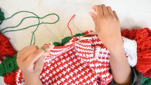 Working the green neckband onto the houndstooth body panel with a wooden hook