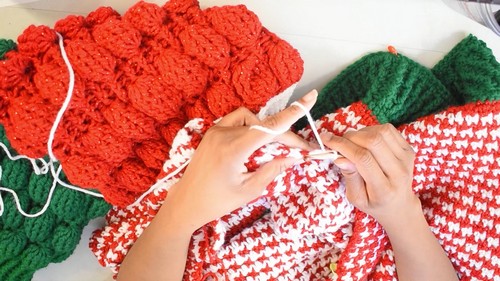 Seaming the red houndstooth body panel to the red bobble sleeve with a white crochet hook